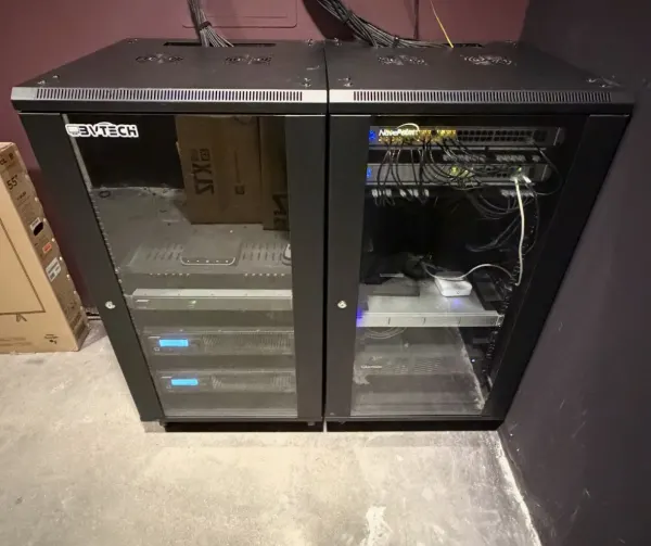 UniFi network core and audio equipment in a glass-door rack installed by BVTech LLC — Jordan Polasek BVTech LLC